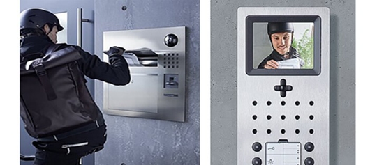 A person dropping off packages at a building's entryway with a video intercom.